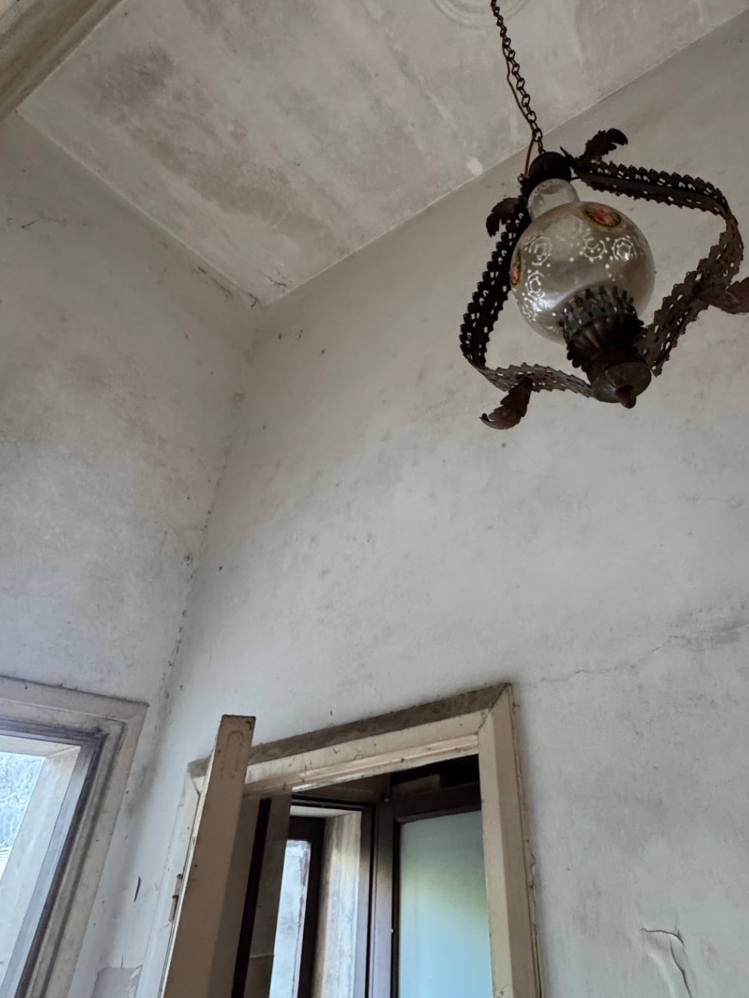 De gang voor de verbouwing: vuile muren, een verweerd houten deurkozijn en een hanglamp die niet brandt